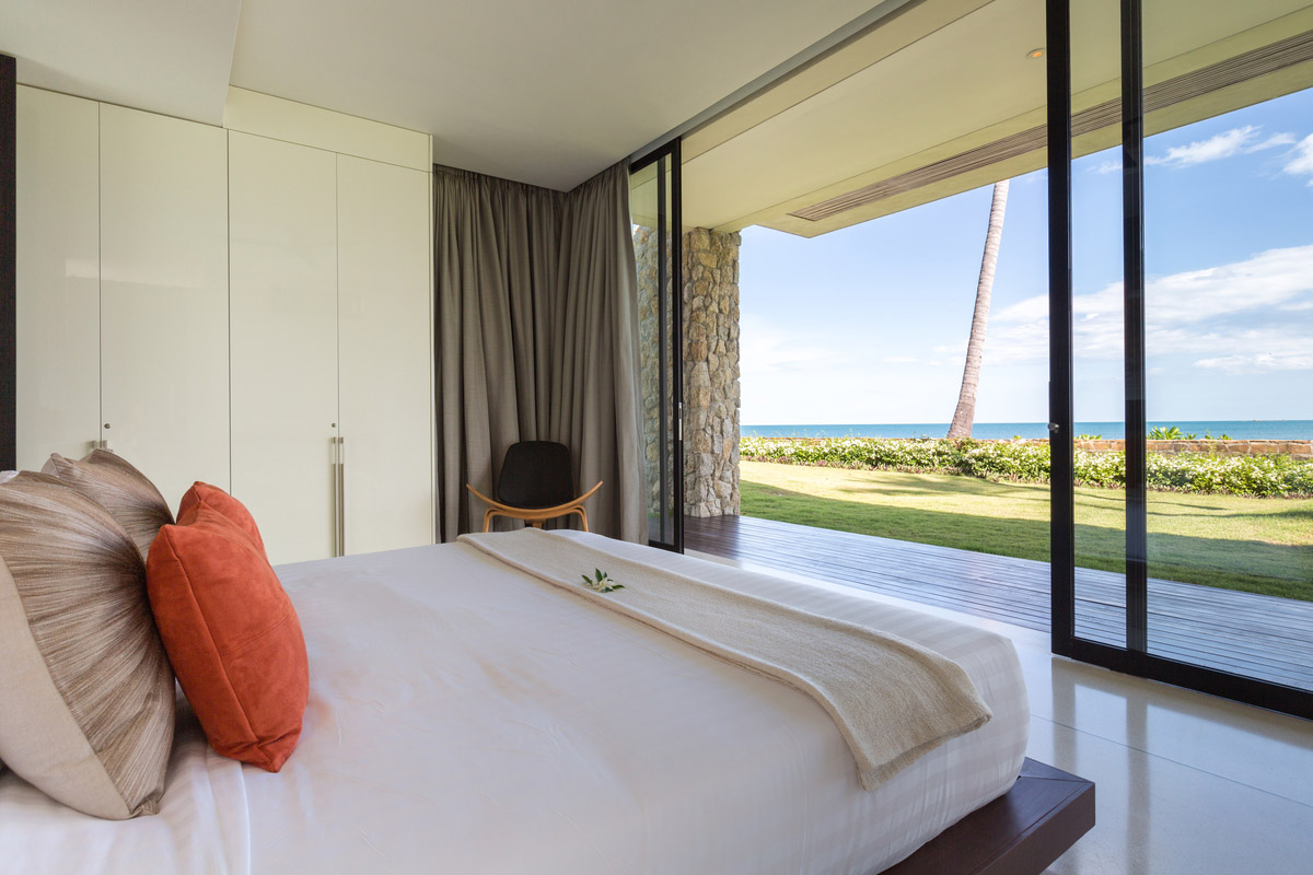 A guest bedroom with glass walls providing full view of the Thailand Gulf.