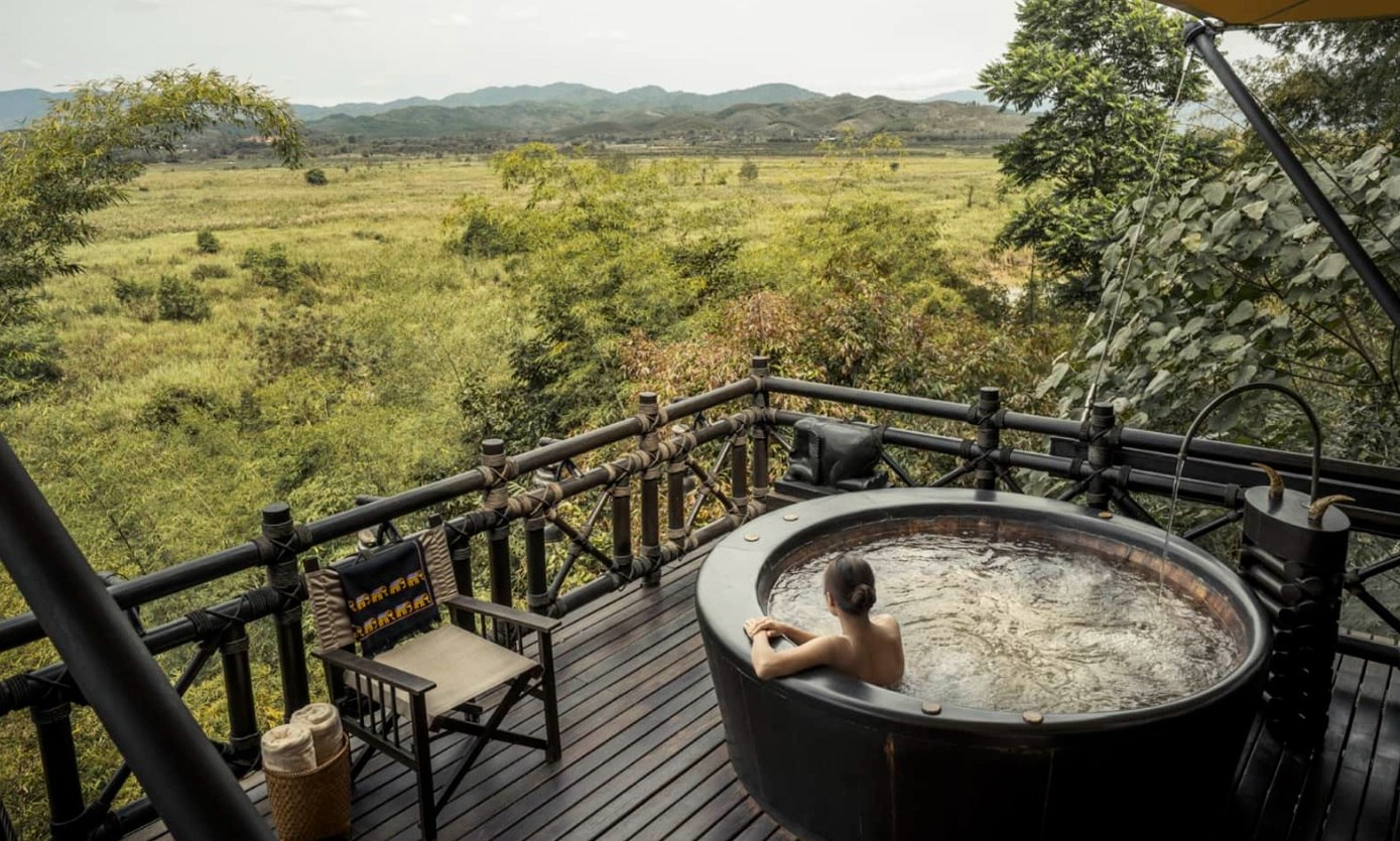 A guest enjoying the view while having a dip at the tub at Four Seasons Tented Camp